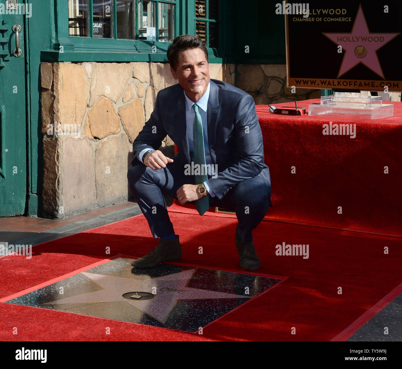 Actor Robe Lowe crouches next to his star during an unveiling ceremony ...