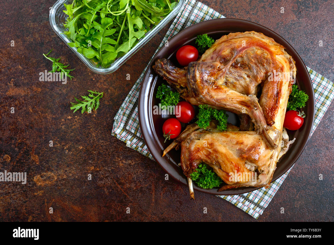 Cooked Rabbit Top View Whole baked rabbit with greens and tomatoes on a plate. Tasty dietary ...