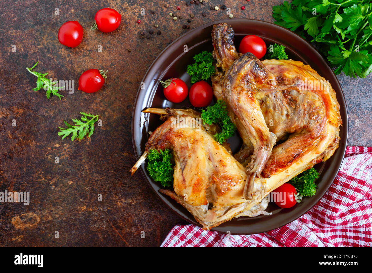 Cooked Rabbit Top View Whole baked rabbit with greens and tomatoes on a plate. Tasty dietary ...