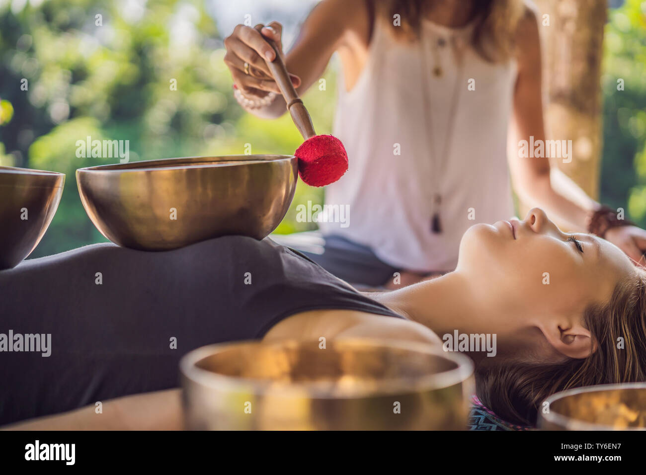 Nepal Buddha copper singing bowl at spa salon. Young beautiful woman