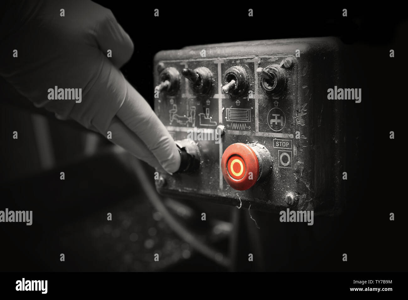 Man pressing button on an industrial machine control panel.  With lighting effect and selective colour Stock Photo