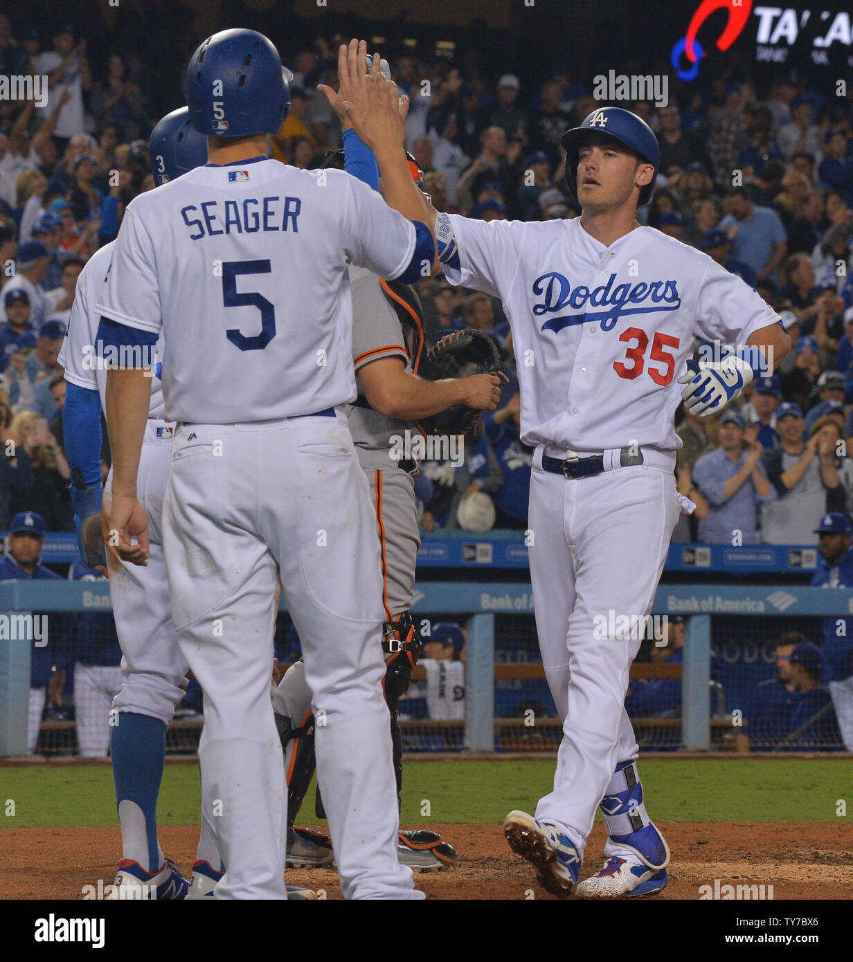 Los Angeles Dodgers' Cody Bellinger is welcomed home by teammates Chris  Taylor and Corey Seager after hitting a mammoth three-run shot to right  field n the third inning, his 39th homer of