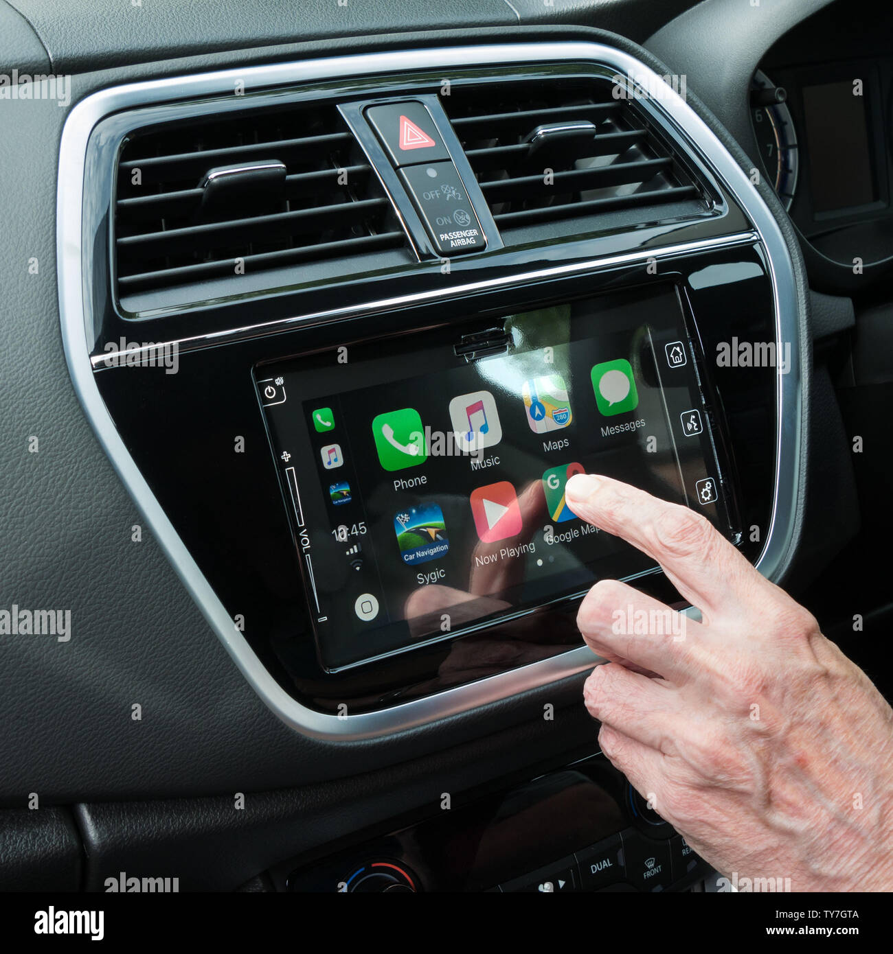 Finger pressing icon on IOS 12 Apple CarPlay home screen menu on Bosch in car dashboard Satnav infotainment head unit in Suzuki S-Cross SX4 vehicle. Stock Photo
