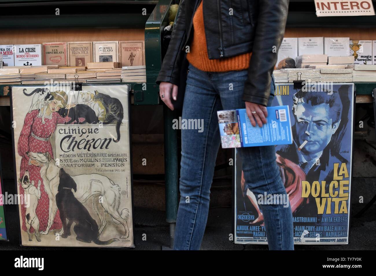 Artpirnt „Clinique Cheron” by Steinlen and a poster from Fellini’s „La Dolce Vita” on book stand in Rome. Stock Photo