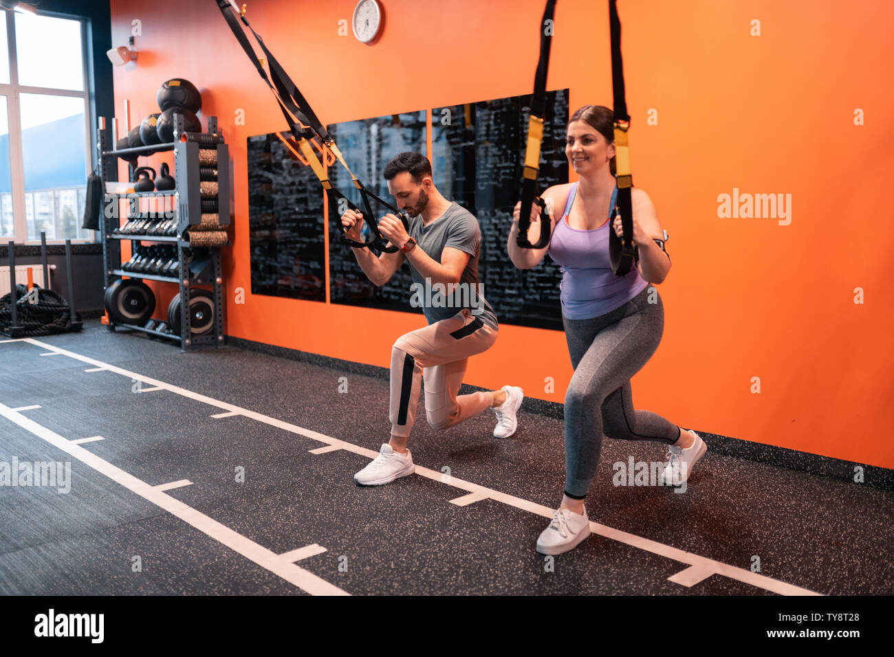 Trainer and his client lunging forward holding TRX straps Stock Photo