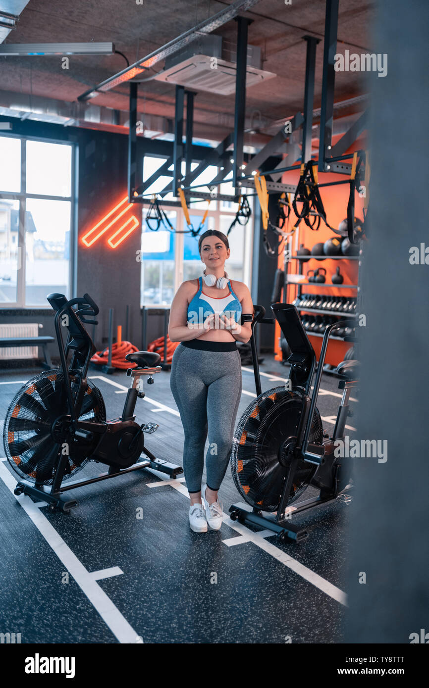 Plump woman standing near exercise cycle in gym Stock Photo Alamy