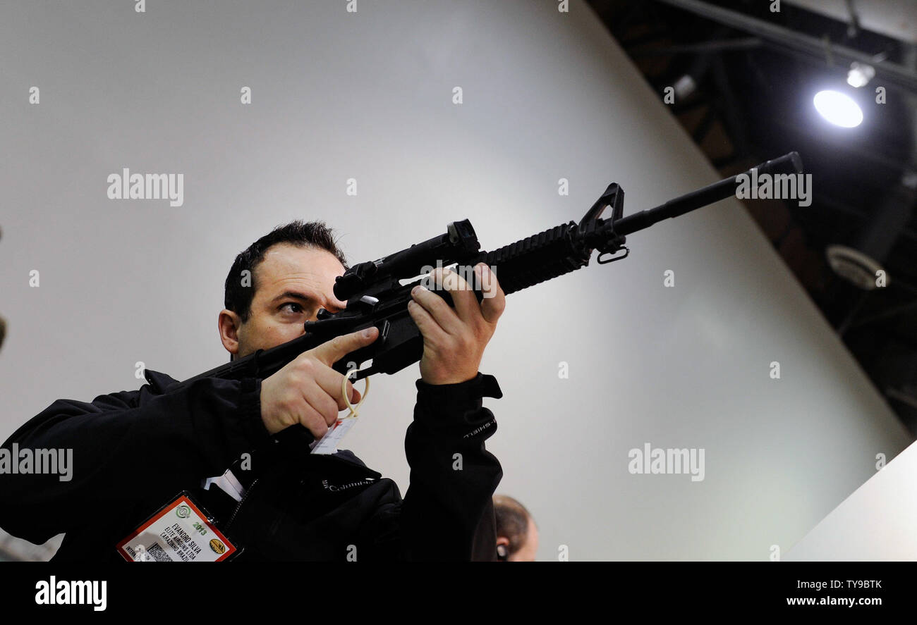 Attendee Evandro Silva of Brazil examines a rifle site at the Trijicon booth at the National Shooting Sports Foundation's 35th annual Shooting, Hunting, Outdoor Trade (SHOT) Show at the Sands Expo and Convention Center January 16, 2013 in Las Vegas. The SHOT Show is the largest annual gathering of shooting professionals with more than 1,600 exhibitors and 60,000 attendees expected.  UPI/David Becker Stock Photo
