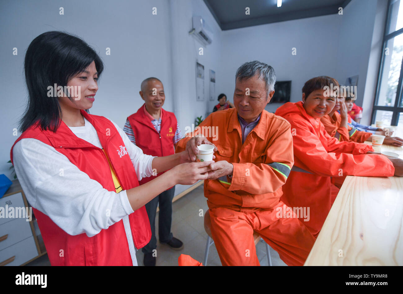 (190626) -- HUZHOU, June 26, 2019 (Xinhua) -- A volunteer offers a cup of water to an outdoor worker in Wuxing District in Huzhou, east China's Zhejiang Province, June 26, 2019. More than 50 public lounges have been put into use in Wuxing District, where weary outdoor workers and common citizens can drink water, rest, charge their phones as well as escape the searing sun. (Xinhua/Xu Yu) Stock Photo