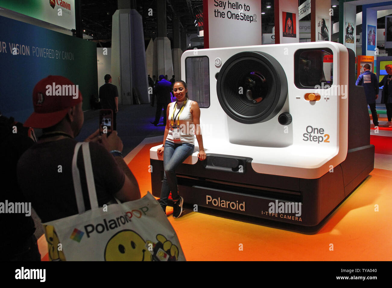 An attendee poses infront of a giant model of a polaroid instant camera,  during the 2018 International CES, at the Las Vegas Convention Center in  Las Vegas, Nevada, January 9, 2018. Photo