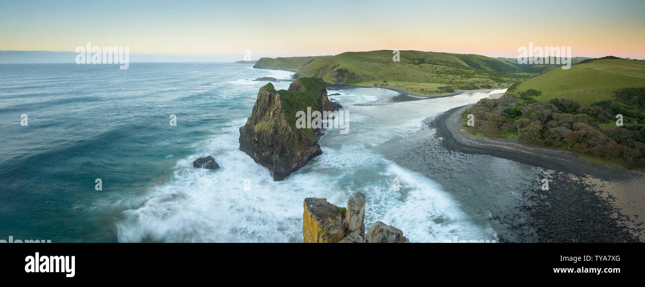 The Hole in the Wall at Coffee Bay is a unique structure with a huge detached cliff that has a giant opening carved through its center by the waves. Stock Photo