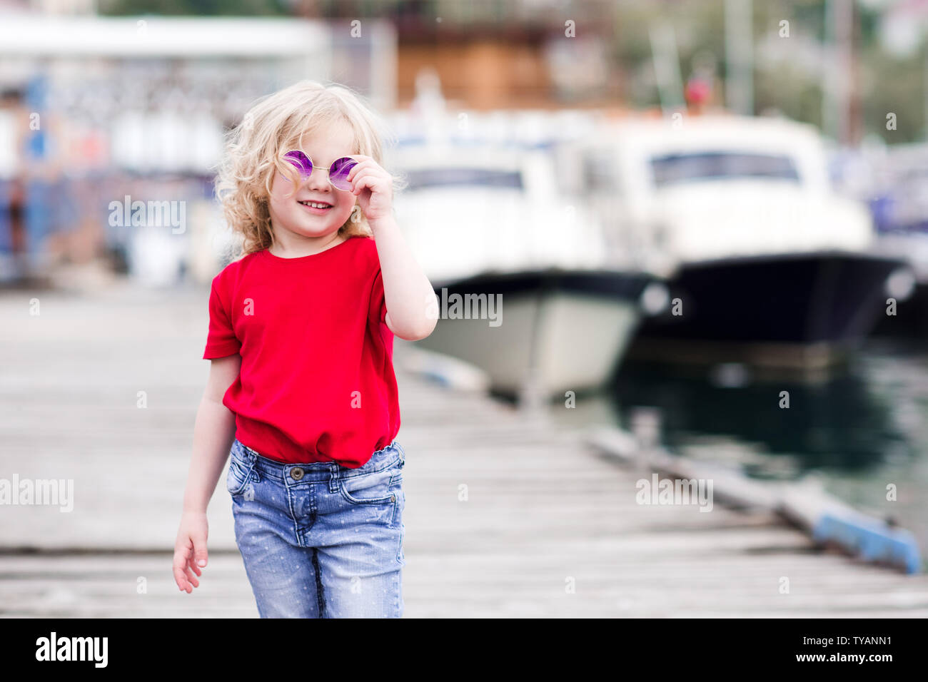 Funny baby girl 34 year old wearing summer clothes outdoors over boats