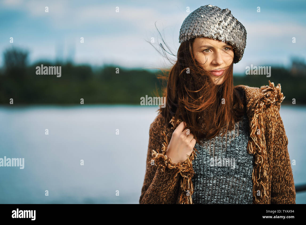 Portrait of beautiful woman posing at the river in the city on windy ...