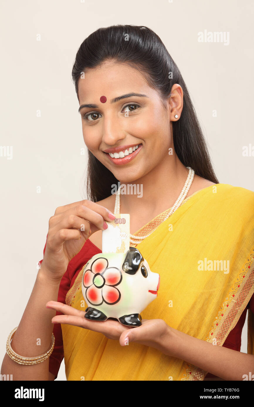 Woman putting banknote into a piggy bank Stock Photo - Alamy
