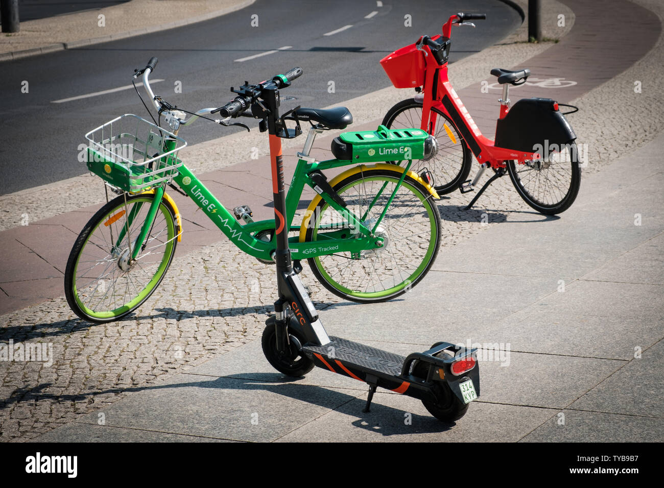 Berlin, Germany - June, 2019: Bike sharing bicycles and electric scooter , escooter or e-scooter on sidewalk in Berlin, Germany Stock Photo