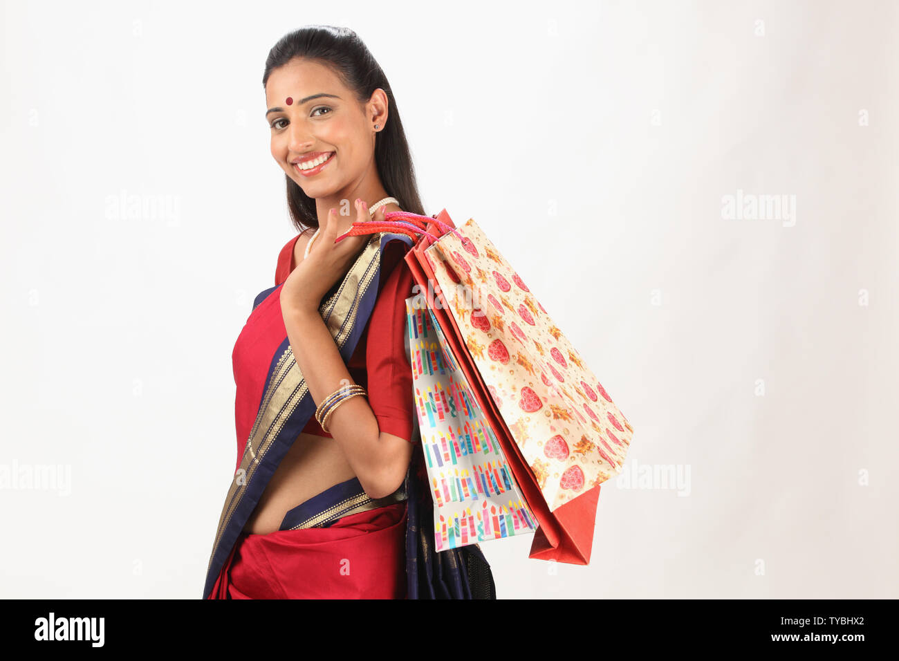 Side profile of a young woman carrying shopping bags and smiling Stock ...