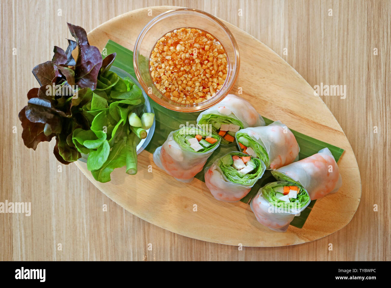 Prawn and fresh vegetable spring rolls served with green salad on a wooden plate Stock Photo