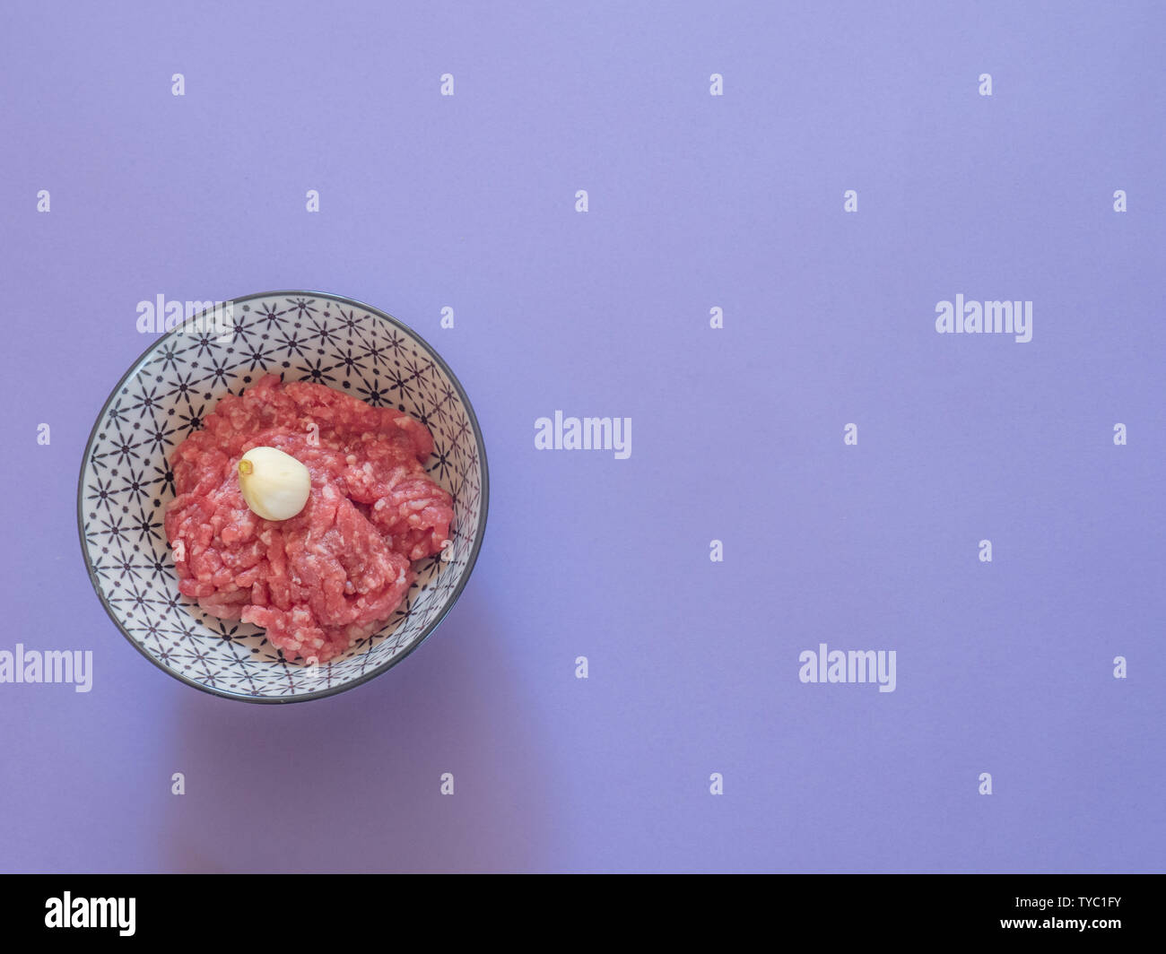 Minced beef meat in a bowl on purple background with copy space Stock Photo