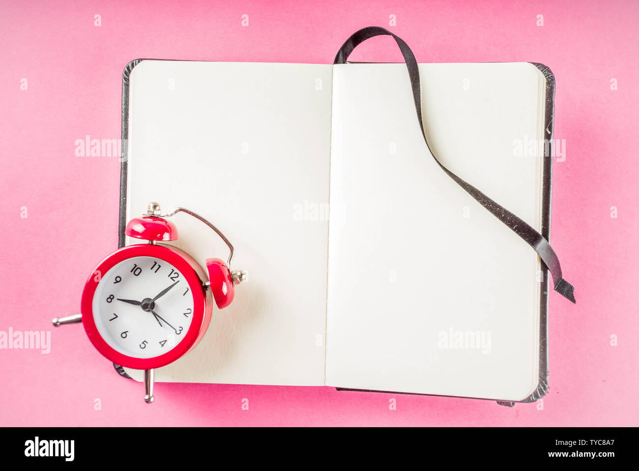 Alarm clock with notepad on bright pink table. Performance, work or study concept, Creative flatlay copy space above Stock Photo