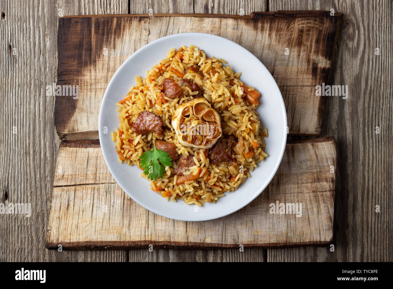 Oriental cuisine. Uzbek pilaf or plov from rice and meat. Wooden rustic background. Top view vith copy space. Stock Photo