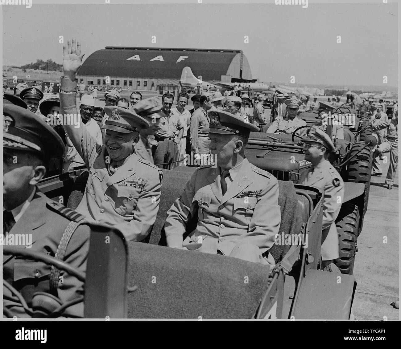 Photograph of General Dwight D. Eisenhower sitting in the back of a jeep with General George C. Marshall, waving to spectators at the airport in Washington. Stock Photo