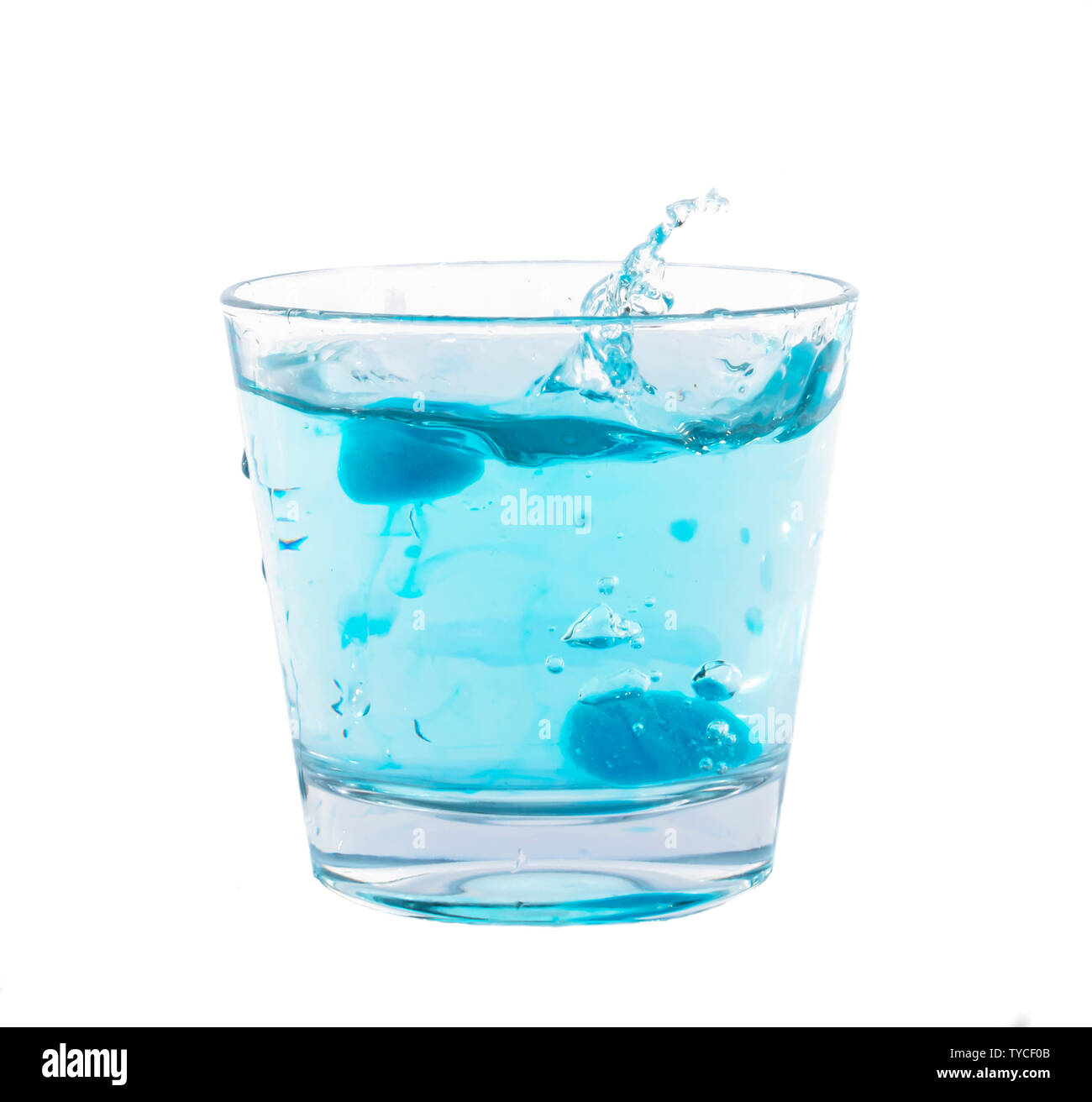 Blue ice cubes splashing into glass of water Stock Photo - Alamy