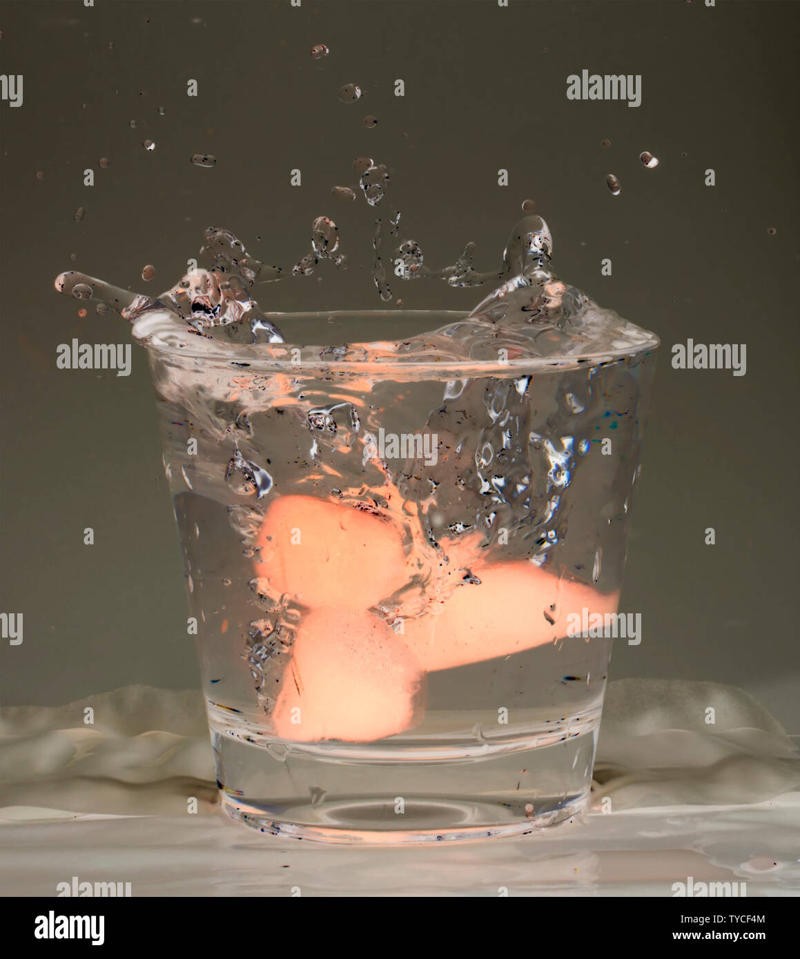Blue ice cubes splashing into glass of water Stock Photo - Alamy