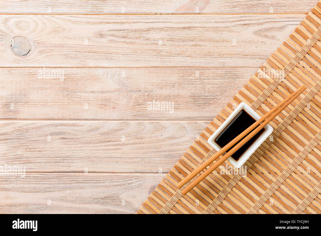 Bamboo Mat And Soy Sauce With Sushi Chopsticks On Wooden Table