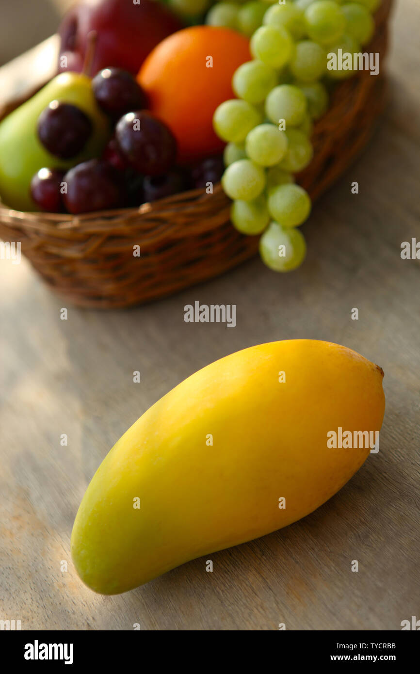 Close up of a mango in front of a fruit basket Stock Photo