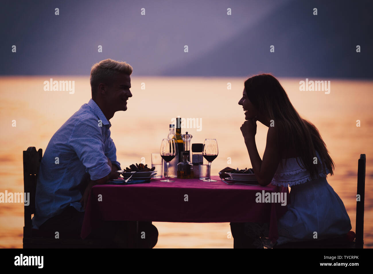 People, vacation, love and romance concept. Young couple enjoying a romantic dinner on beach. Stock Photo