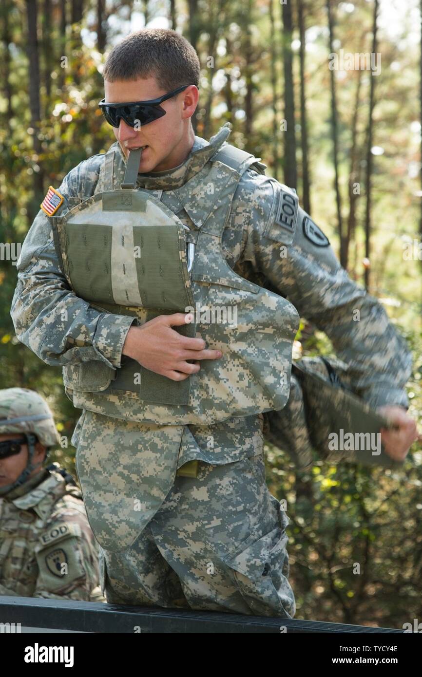 U.S. Army Pfc. Alec Wheeler, an Explosive Ordnance Disposal soldier, assigned to the 797th Ordnance Company (EOD), 79th Ordnance Battalion (EOD), 71st Ordnance Group, straps on his Improved Outer Tactical Vest at the safe zone on Camp Minden, Nov. 1, 2016. Wheeler was preparing to begin a controlled burn on a decaying ammunition bunker. Stock Photo