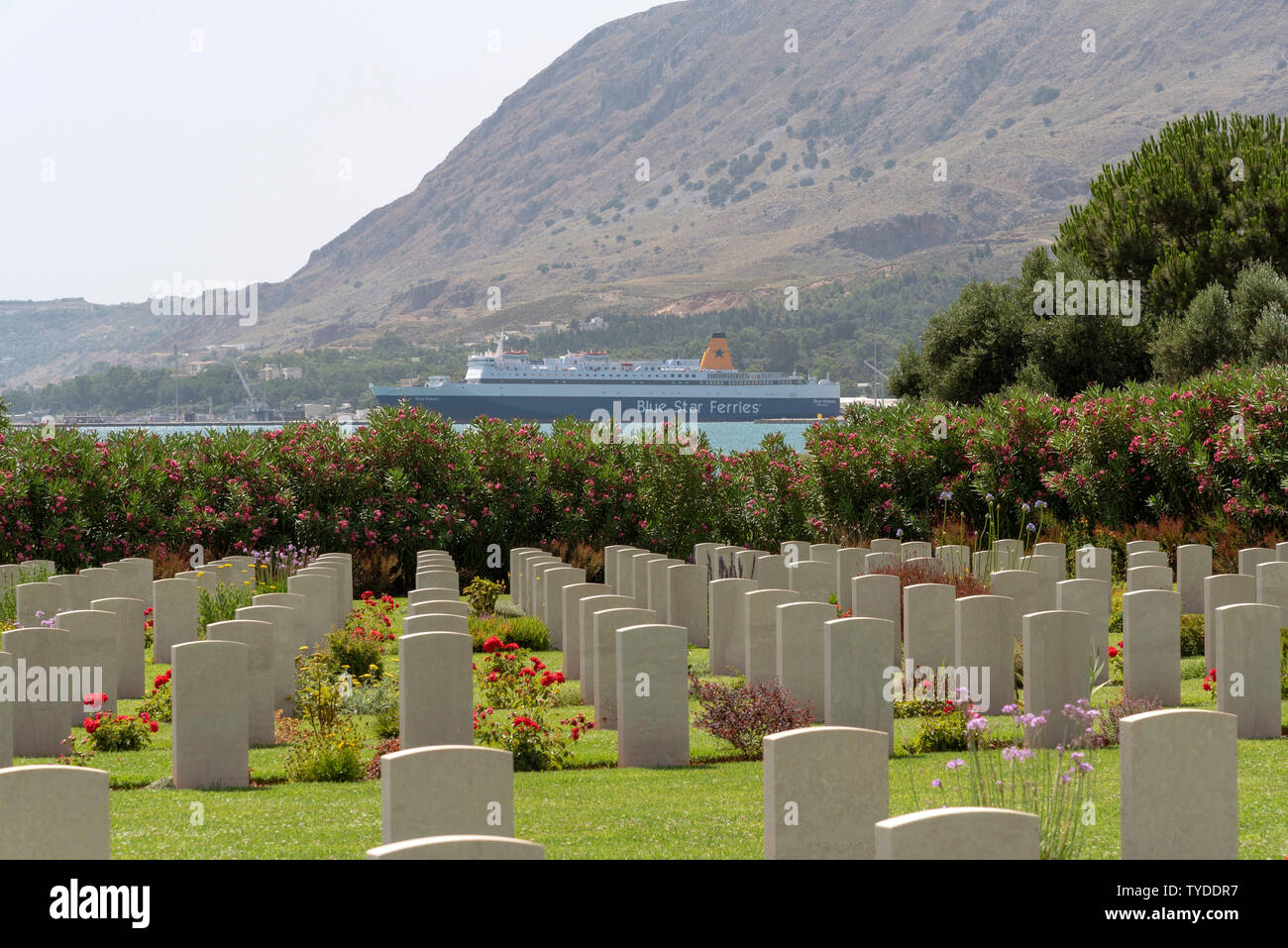 Suda Bay War Cemetery, Crete, Greece. June 2019. Looking towards the Port of Souda and a Greek ferry, the Blue Galaxy. Stock Photo