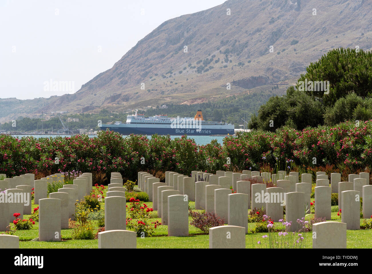 Suda Bay War Cemetery, Crete, Greece. June 2019. Looking towards the Port of Souda and a Greek ferry, the Blue Galaxy. Stock Photo
