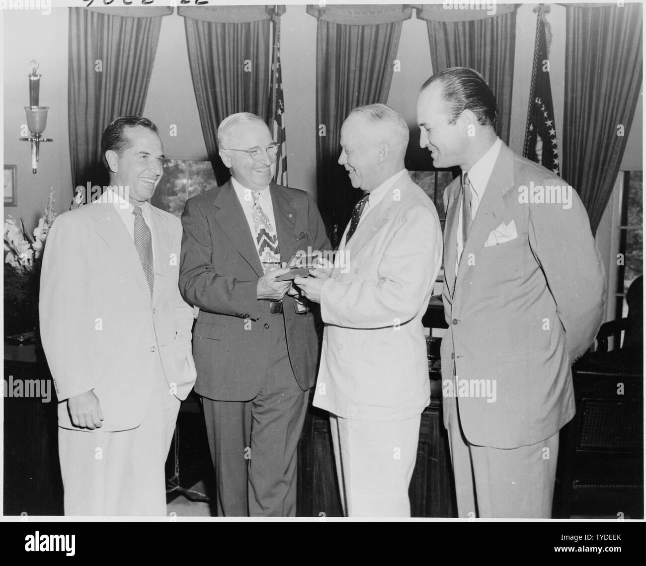 Photograph of President Truman in the Oval Office, receiving a gold pass to all games of the All-America Football Conference during the 1949 season: (left to right) Robert Embry of the Baltimore Colts; the President; Commodore O. O. Kessing, Commissioner of the All-America Football Conference; and Walter Driskill, President and General Manager of the Baltimore Colts. Stock Photo