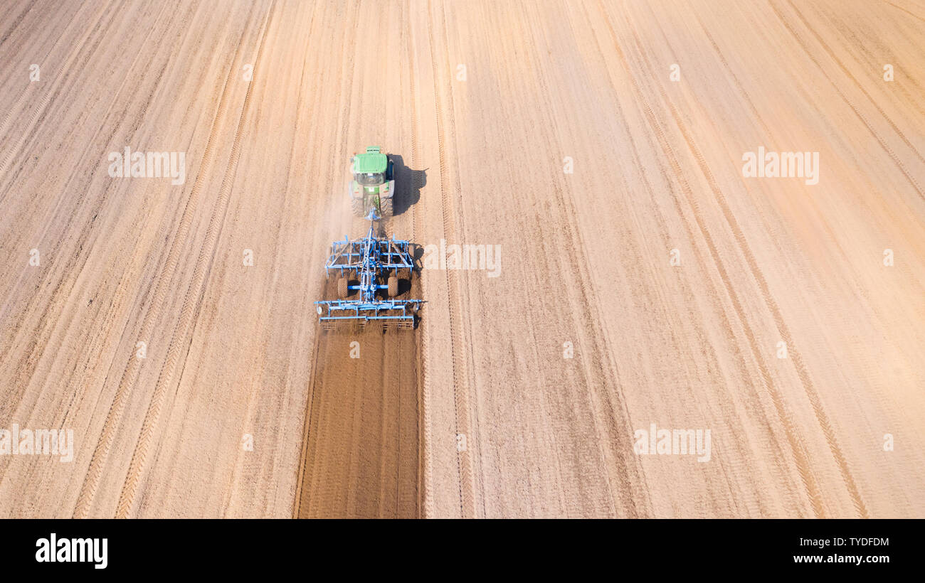 Tractor plows the field, top view. The agricultural field is prepared for planting vegetables. Tractor work in farming. Stock Photo
