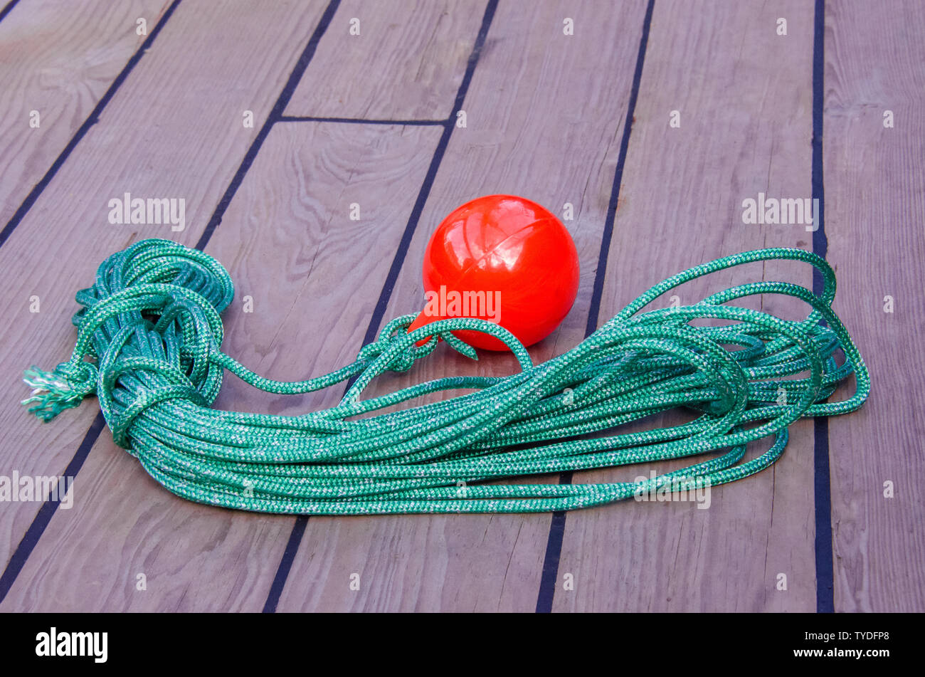 Sea tackle to facilitate the supply of the mooring cable to the shore. A coil of thin green rope with a plastic red ball on the end. Stock Photo