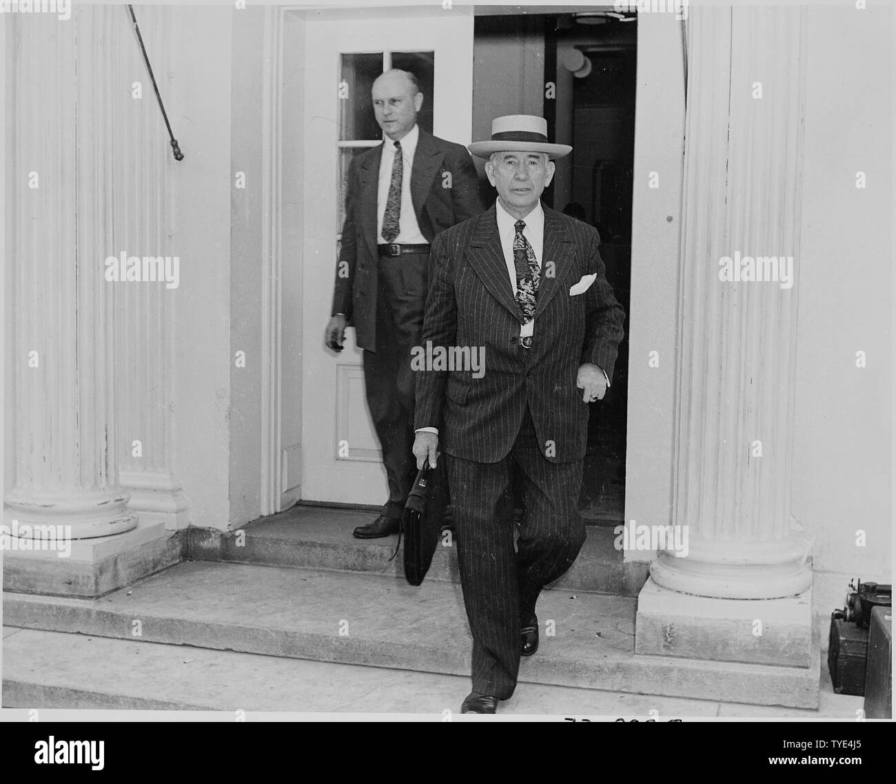 Photograph of Senator Alben Barkley and an unidentified man, leaving the White House on the occasion of the announcement of the Japanese surrender ending World War II. Stock Photo