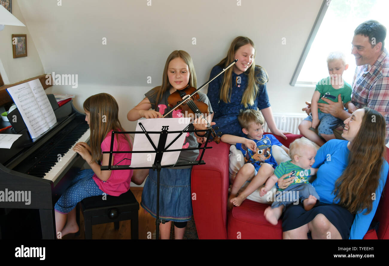25 June 2019, Saxony, Schönwölkau: Emma (front, r) and Stefan Fenchel (r) sit in her living room with their six children and make music. The Bavarian and the Canadian moved from Bavaria to Leipzig in 2004 and now live in Schönwölkau with their six children, three girls and three boys between 12 and one year old. In the small village they have built an old house and enjoy the country life with their children. While at school in the neighboring city the German language is of course spoken, the whole family speaks English at home. (to dpa 'Where the children rich in Germany live - and how') Photo Stock Photo