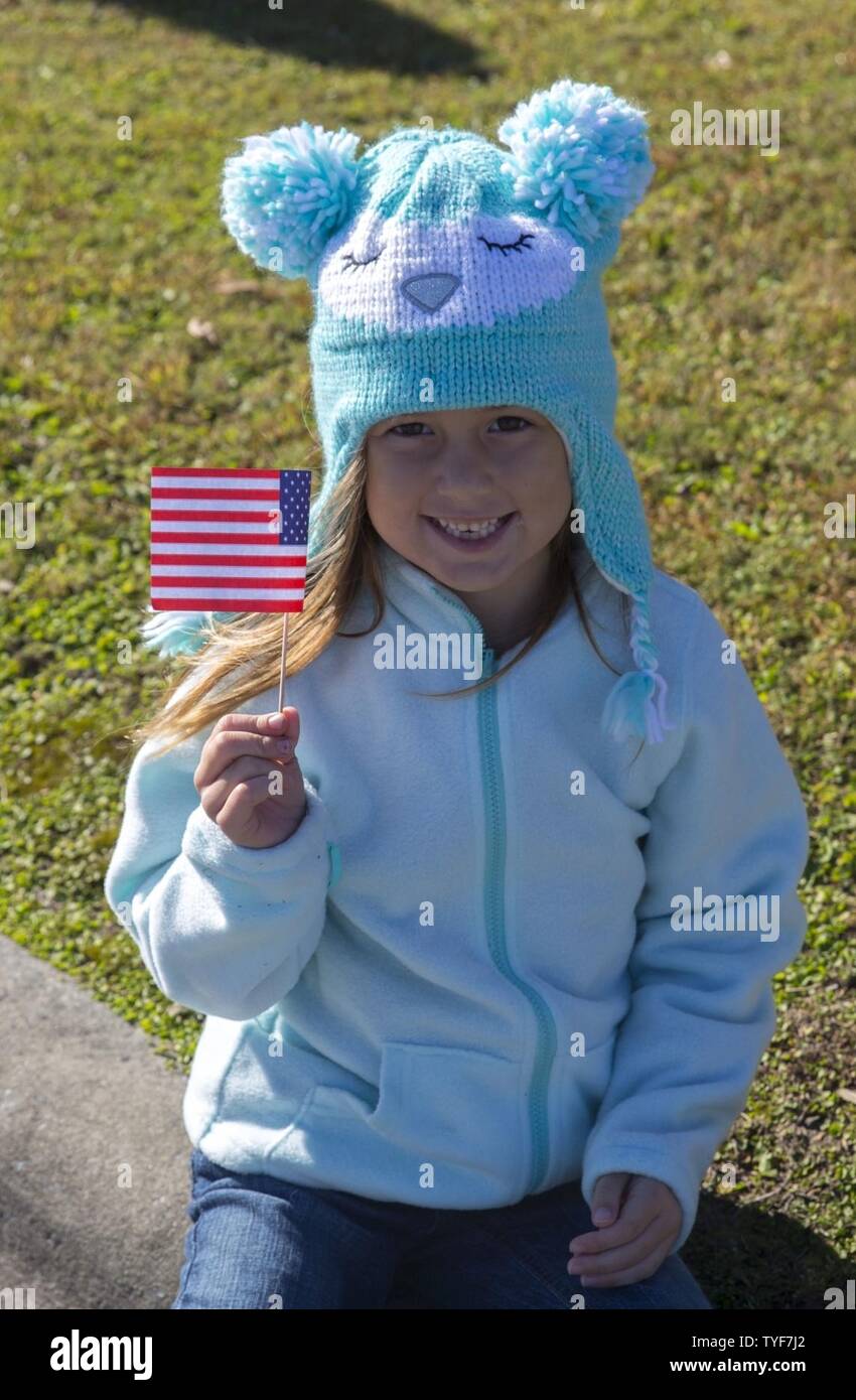 A young girl poses with an American flag during the 21st Annual Veterans Day Parade in Jacksonville, N.C., Nov. 5, 2016. The Veteran’s Day Parade, hosted by Rolling Thunder Inc. Chapter NC-5, was observed by veterans, service members, and residents of Jacksonville and showed support for members of the armed forces. Stock Photo