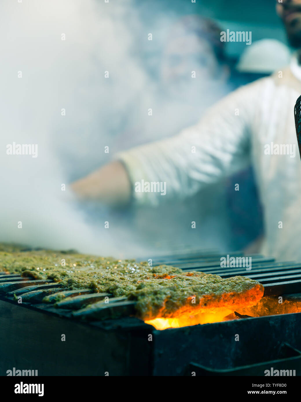 Man grilling Kebabs over charcoal grill with smoke at Qureshi Kabab Corner in Old Delhi India Stock Photo