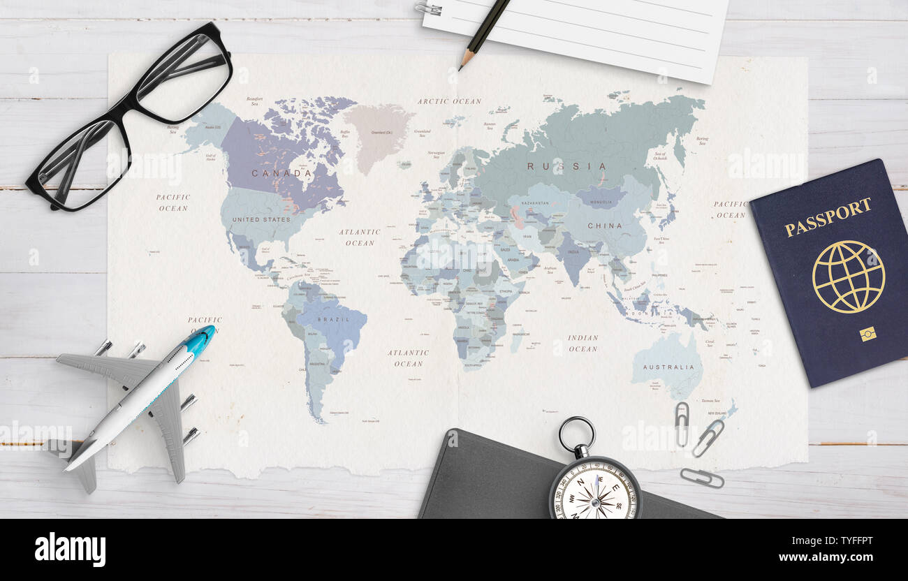 Concept of travel organization. Airplane model, passport, compass, glasses, pad and pencil on world map. Copy space in the middle. Top view, flat lay. Stock Photo
