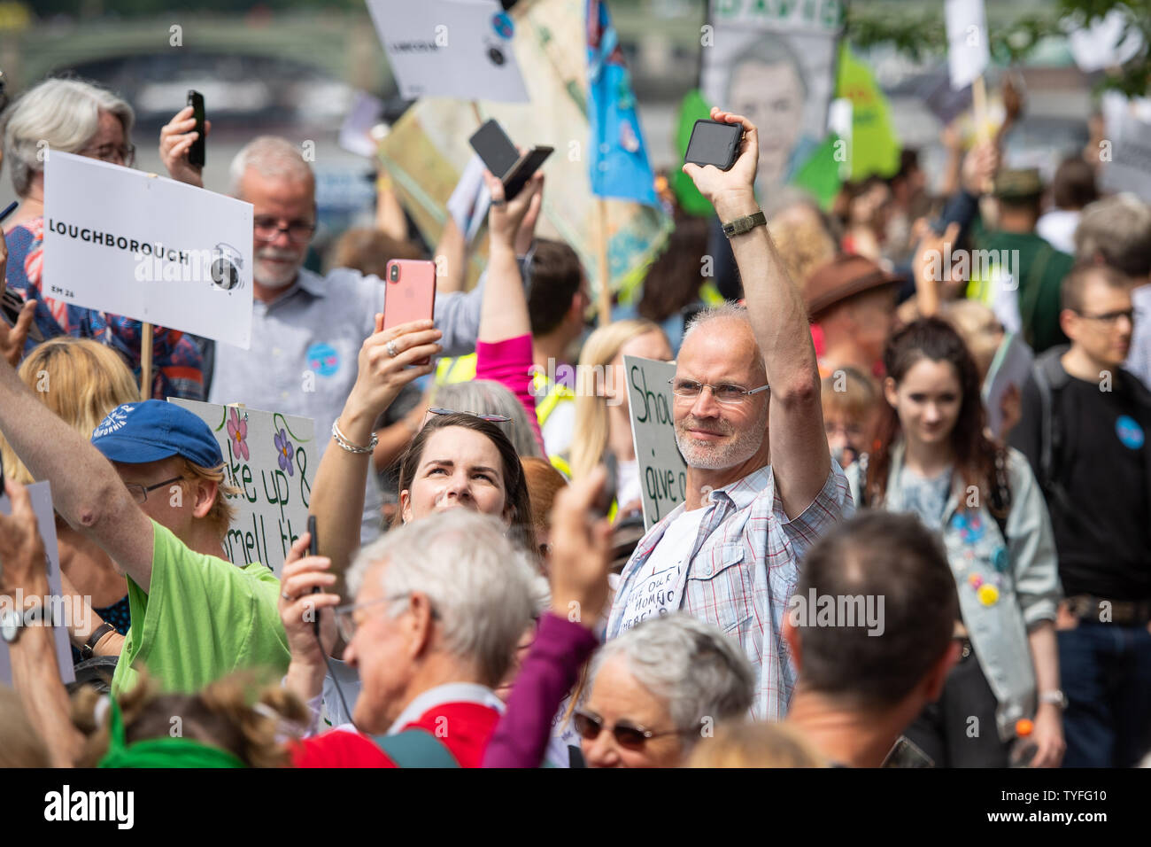 Environmental campaigners sound their mobile phone alarms together as they take part in the 'Time Is Now' mass lobby and protest in Westminster, London. Stock Photo