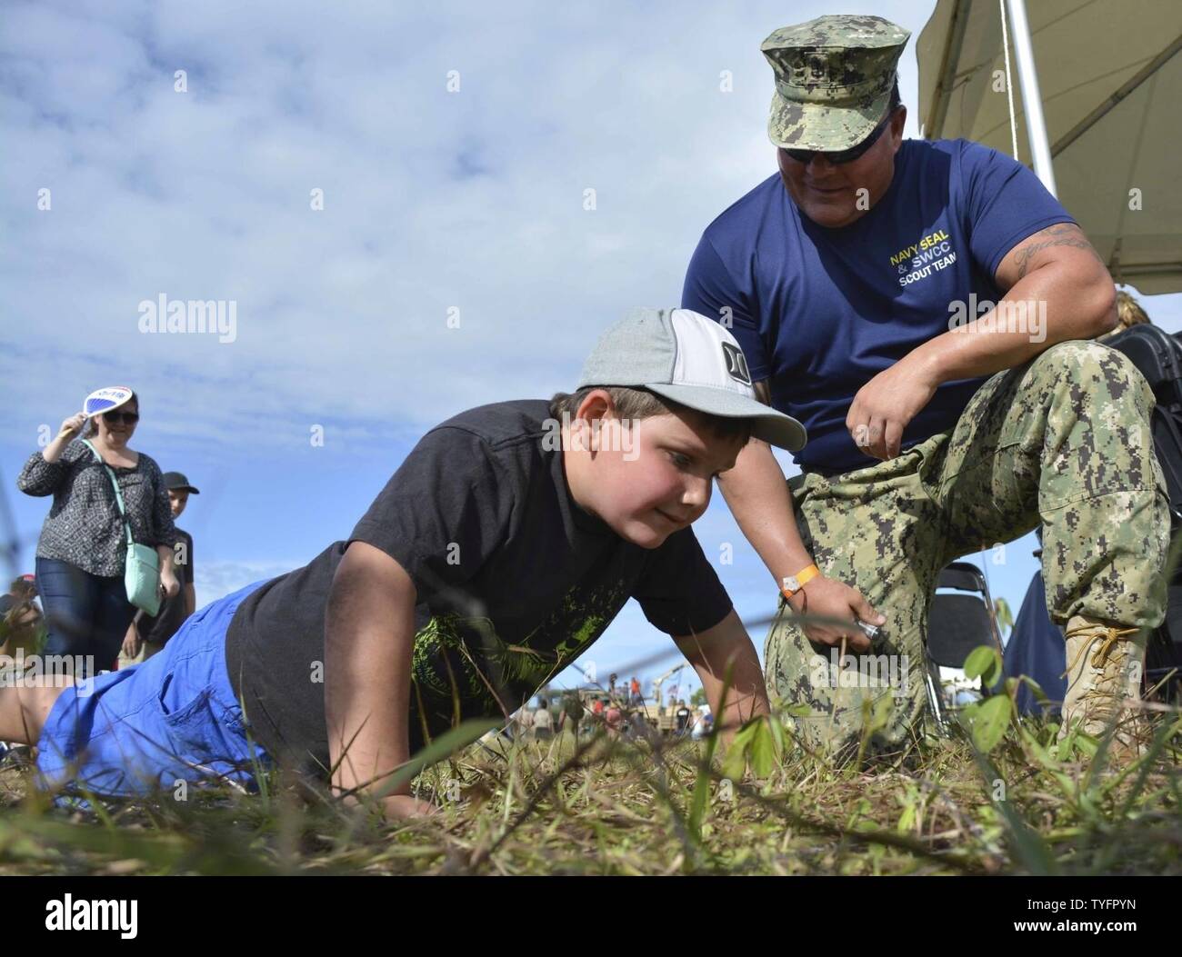 STUART, Fla. (Nov. 6, 2016) - Chief Petty Officer Joseph Schmidt, assigned to the Navy SEAL and SWCC Scout Team, encourages a young fan to do pushups at the 2016 Stuart AirShow. The Scout Team conducts outreach to community groups and athletic teams to inform them about the Naval Special Warfare training mission. Stock Photo