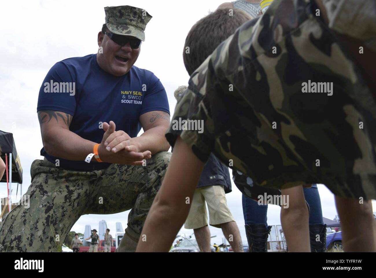 STUART, Fla. (Nov. 6, 2016) - Chief Petty Officer Joseph Schmidt, assigned to the Navy SEAL and SWCC Scout Team, encourages a young fan to do pushups at the 2016 Stuart AirShow. The Scout Team conducts outreach to community groups and athletic teams to inform them about the Naval Special Warfare training mission. Stock Photo