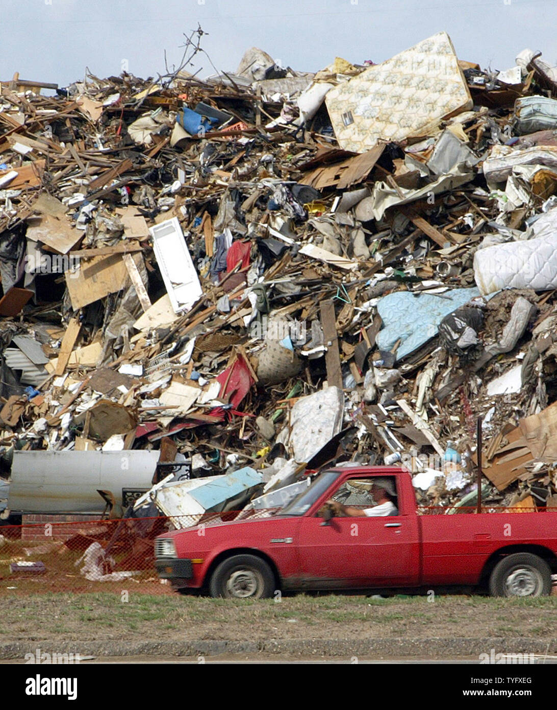A New Orleans resident drives past a mountain of trash, which is being referred to as simply 'the pile', as it continues to grow in the Lakeview neighborhood of New Orleans November 14, 2005.  The pile is created by residents gut and repair their houses as they return to their flood-damaged homes in the aftermath of Hurricane Katrina.  About 80 percent of the city was  submerged when the nearby 17th Street Canal levee was breached during the hurricane.  Now, contractors with trucks and small bulldozers move constantly through the city collecting curbside heaps of soggy drywall, downed trees li Stock Photo