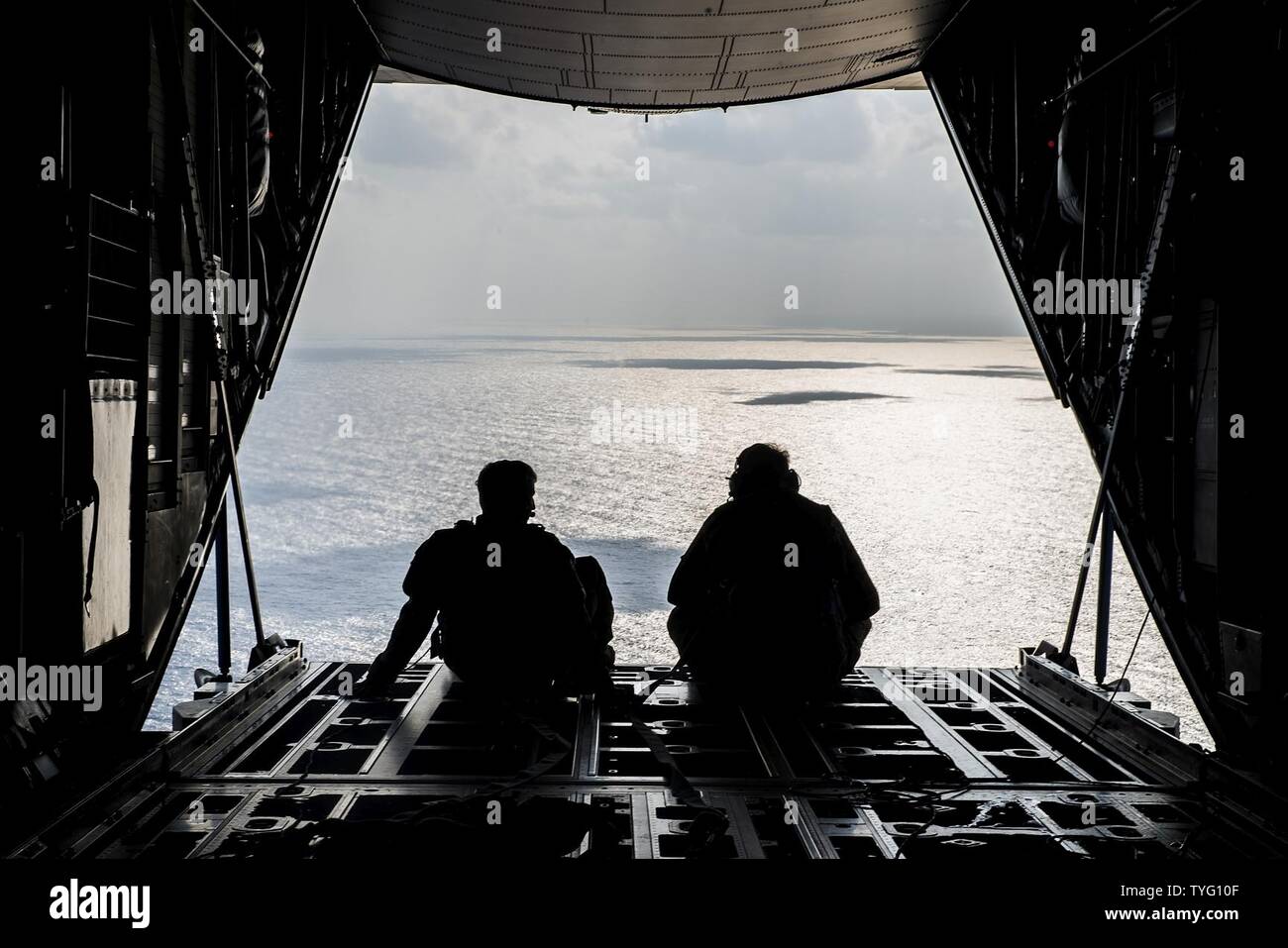 Senior Airman Timothy Manzer and Staff Sgt. Korey King, 17th Special Operations Squadron loadmasters, look out over the ocean after refueling HH-60 Pave Hawks from 33rd Rescue Squadron and Japan Air Self-Defense Force during exercise Keen Sword 17, Nov. 7, 2016, near Okinawa, Japan. For more than 50 years, the U.S.-Japan Alliance has been the foundation of peace and security in Northeast Asia and the cornerstone of U.S. engagement in the region. In 1960, Japan and the U.S. signed the Treaty of Mutual Cooperation and Security. The alliance plays an indispensable role in ensuring the security an Stock Photo