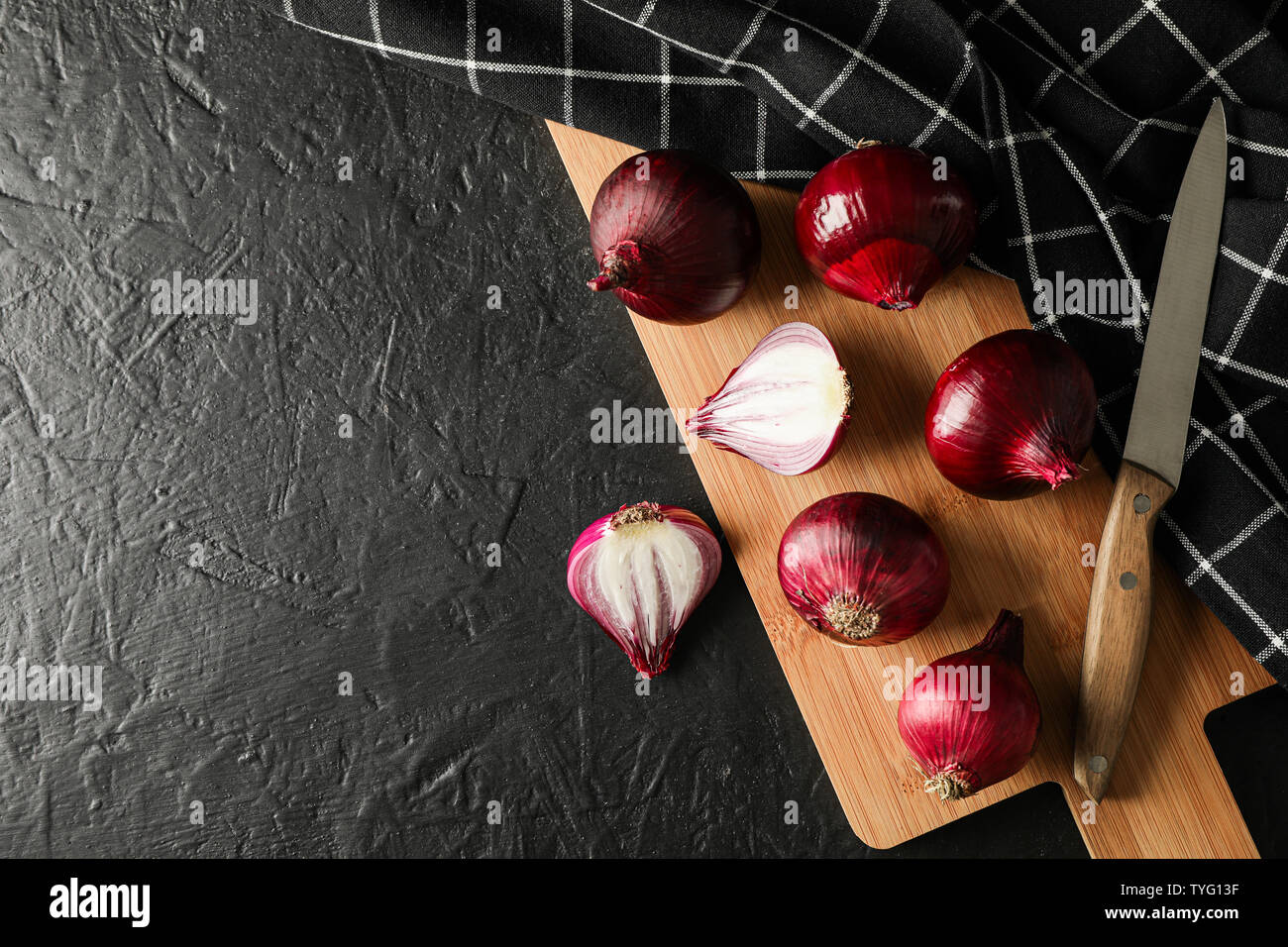 Composition with red onion, cutting board and knife on black background ...