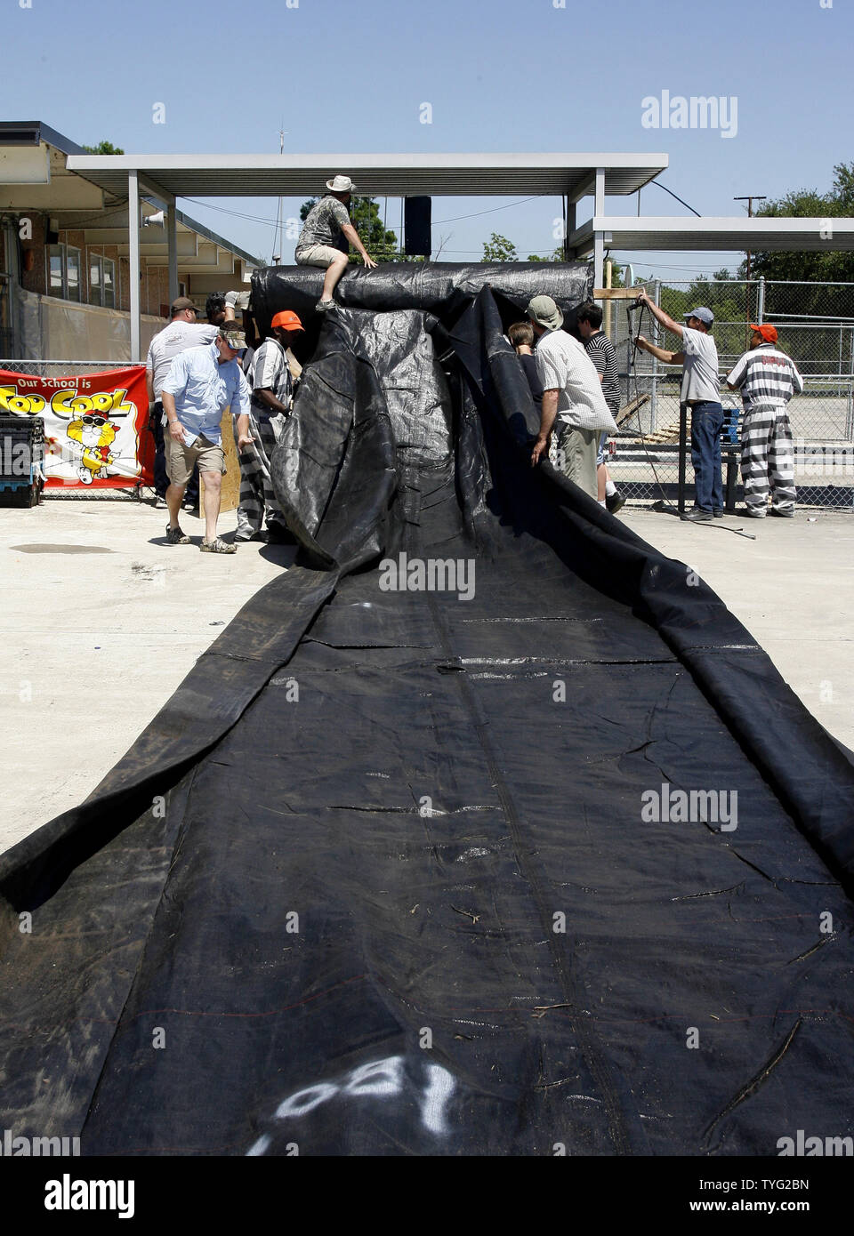 Prison inmates and volunteers unroll a section of 'aqua dam,' a rubber bladder that is filled with water to create a temporary dam, in Stephensville, Louisiana, May 14, 2011. Residents of St. Mary Parish were preparing for high water after the U.S. Army Corps of Engineers opened the Morganza Floodway to divert water from the cresting Mississippi River away from downriver cities including Baton Rouge and New Orleans.  UPI/A.J. Sisco. Stock Photo