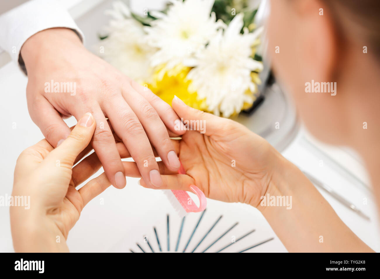Pedicurist looking at fingernails of man prior to manicure Stock Photo