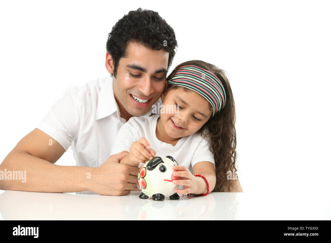 Girl putting coin into a piggy bank with her father Stock Photo - Alamy