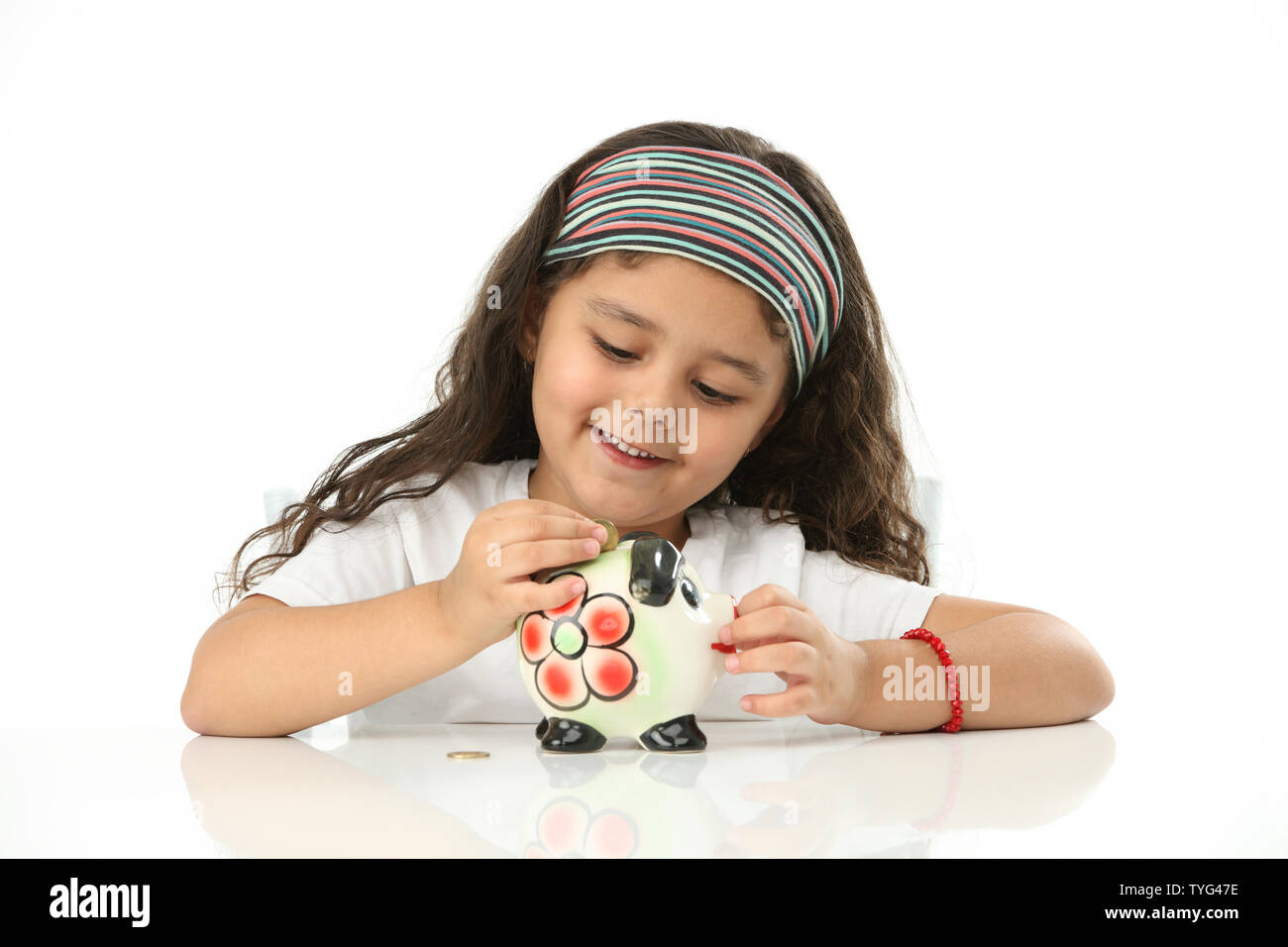 Girl putting coin into a piggy bank Stock Photo - Alamy